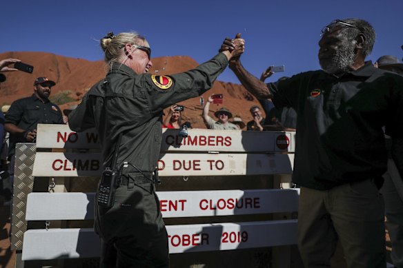 Ranger Lynda Wright celebrates with Chair of Uluru-Kata Tjuta national park, Sydney James, after placing the new sign of the permanent closure of the Uluru climb on the final day the climb is allowed.