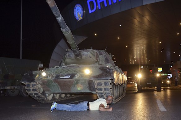 A man lays in front of a tank in the entrance to Istanbul's Ataturk airport.