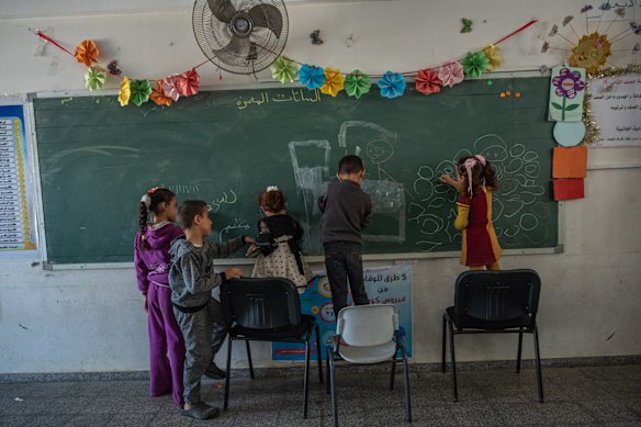 Palestinian children use chalk to draw on a chalkboard in an UNRWA school, after violent Israeli raids on the city of Beit Hanoun in northern Gaza on May 14, 2021 in Gaza City, Gaza. More than 100 people in Gaza and seven people in Israel have been killed in continued cross-border rocket exchanges as violence continues to escalate bringing fears of war. The escalation, which erupted May 10, comes after weeks of rising Israeli -Palestinian tension in East Jerusalem, which peaked with violent clashes inside the holy site of Al-Aqsa Mosque.