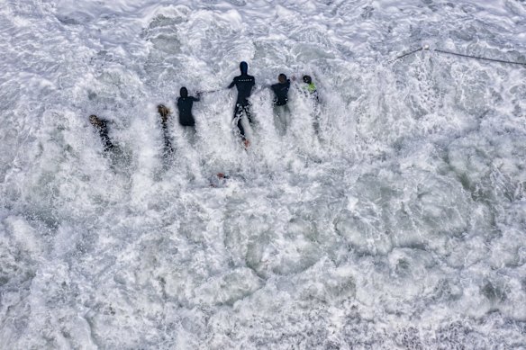 Children hang onto ocean pool fencing as big waves pound the shore in Narrabeen.
25 August, 2021.