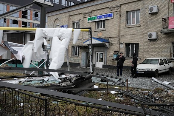 A woman takes a photo of the consequences of Russian shelling in Kyiv.