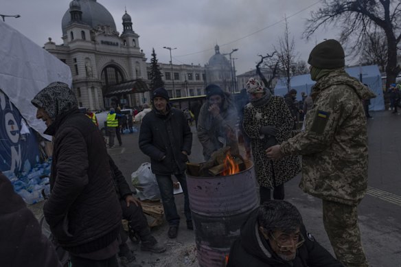 People keep warm by fires outside the main rail terminal in Lviv, Ukraine.