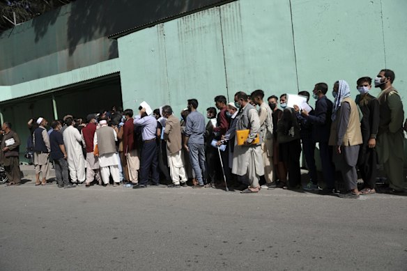 Afghans wait in long lines for hours  to get visas in front of the Iranian embassy, in Kabul, Afghanistan. Officials say Taliban fighters have entered Kabul and are seeking the unconditional surrender of the central government. 
