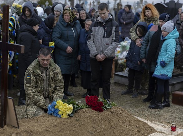 Sergey Zhelisko kneels next to the grave of his son, Ukrainian soldier Dmitry Zhelisko in Rusyn. Zhelisko died fighting the Russian army near the town of Kharkiv.