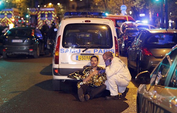 A medic tends to a man in shock on a Paris street. Gunfire and explosions in multiple locations erupted in the French capital with early casualty reports indicating at least 60 dead.