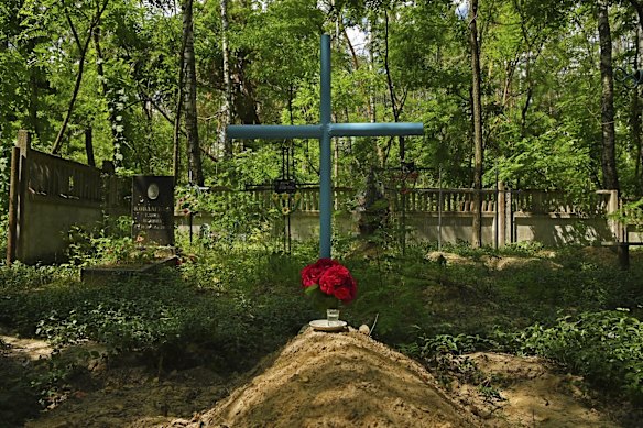 A bouquet of flowers and a shot of vodka sits atop an unmarked fresh grave at the cemetery in Yahidne. 