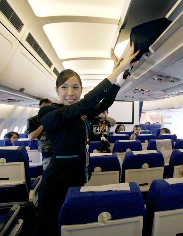 PC Air transsexual flight attendant Chayathisa Nakmai, 24, puts a passenger's luggage in the overhead compartment.