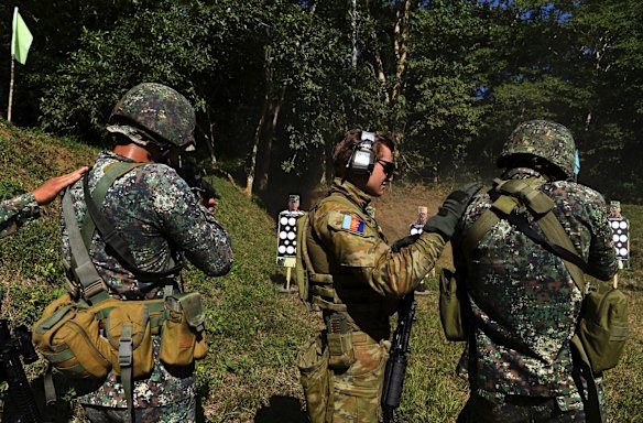 Private Brock Francis (2nd from right) with the 8th/9th Royal Australian Regiment and Land Mobile Training Team taps the shoulder of his Filipino counterpart during training at the firing range.