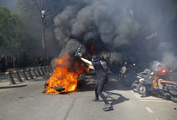 A protester throws a scooter onto a fire during a yellow vest protest in Paris.