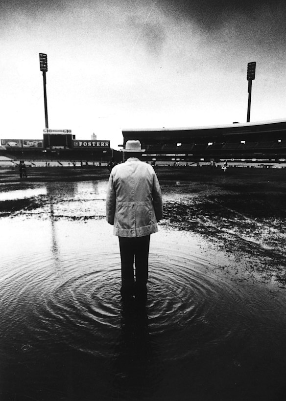 Goal umpire Phil Goss stands in a puddle behind the posts to officiate in torrential rain during the Sydney Swans versus Carlton under 19 Australian Rules football match at the Sydney Cricket Ground in June 1991.