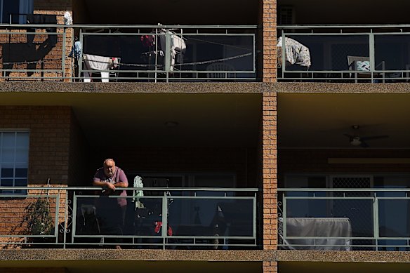 A man looks out over the street from the balcony of his apartment building in Bexley during the COVID-19 lockdown, in the Bayside LGA which is under additional restrictions.