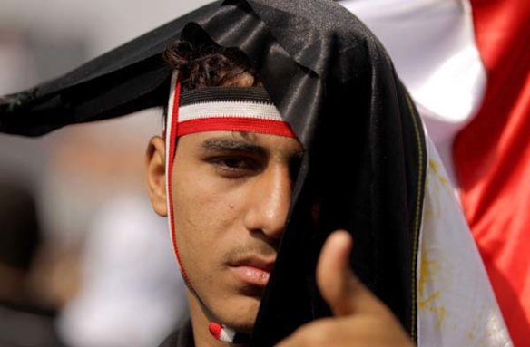 An Egyptian anti-government protester covered with a national flag gives a thumbs-up as he takes part in a protest in Cairo's Tahrir square on February 9.