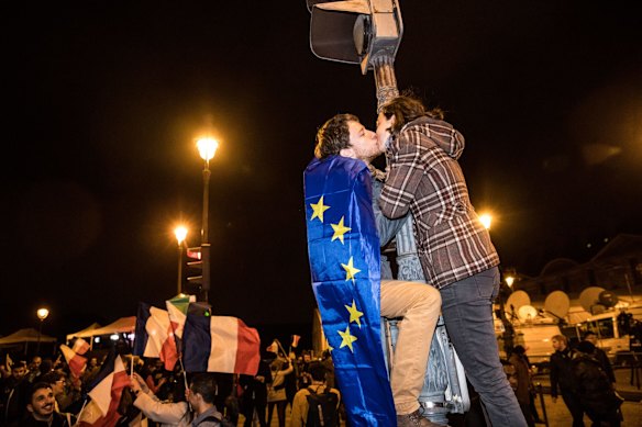 Supporters of Emmanuel Macron, French presidential candidate, not pictured, wear a European Union flag as they kiss after Macron delivered a speech in front of the Pyramid at the Louvre Museum in Paris, France, on Sunday, May 7, 2017. Macron pledged to unite France's rifts after his victory over Marine Le Pen in the presidential election, saying that he'll work to address the concerns that were exposed during one of the most divisive campaigns of recent history. Photographer: Christophe Morin/Bloomberg