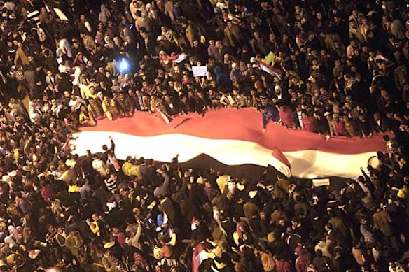 Egyptians wave a giant Egyptian flag at Tahrir Square after President Hosni Mubarak resigns.