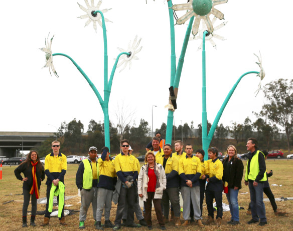 Artist Sharyn Egan (centre) and architect Linda Kennedy (left) with the crew from Productivity Bootcamp, Quakers Hill, in front of a sculpture called the <em>Flannel Flower.</em>