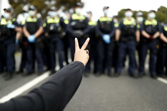 An anti-lockdown protester forms a peace sign during a sit-in along Burnley Street in Richmond in Melbourne.