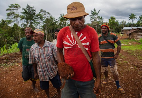 Uali Yalumi, holding a clump of soil showing how difficult it is to grow vegetables in their gardens in Mougulu.