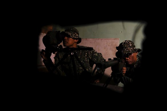 Philippine marine snipers look through their scopes in a hide inside a building during training.