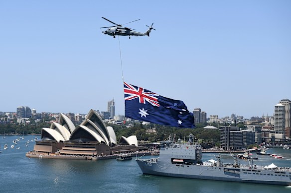 A Royal Australian Navy MH-60R Seahawk helicopter flies an Australian flag over Sydney Harbour during Australia Day celebrations.