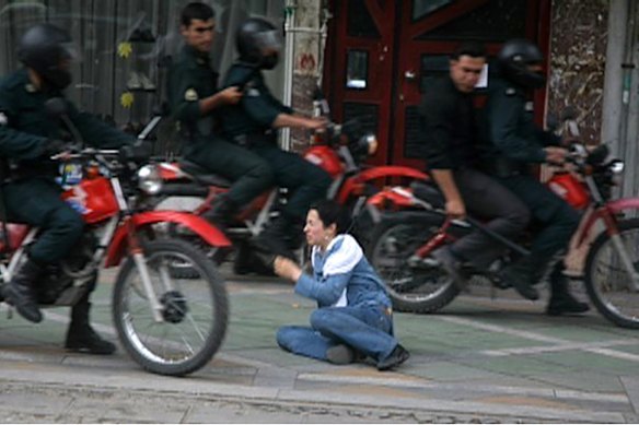 Security personnel look at a woman sitting on the ground as they ride past in Tehran in this photograph made available June 21, 2009. Pro-reform clerics in Iran stepped up criticism of the authorities on Sunday after more than a week of unprecedented popular defiance against the leadership of the Islamic Republic.