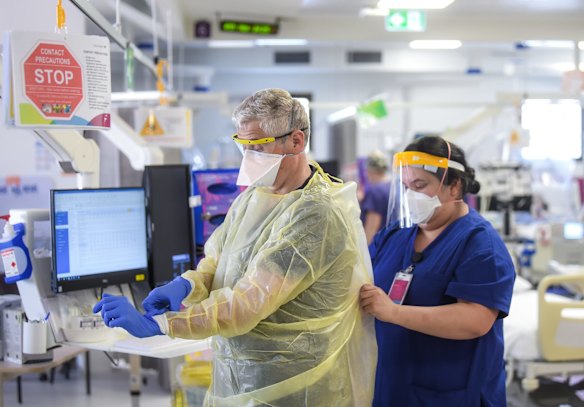Professor Craig French, Director Intensive Care Western Health is helped with his PPE.