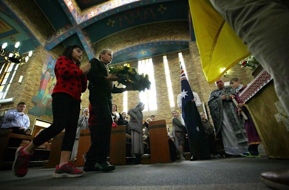 Members of the Australian Ukrainian community prepare to lay a wreath during a prayer vigil for those killed in the crash of Malaysia Airlines flight MH17, at the St Andrew's Ukrainian Catholic church in Sydney July 19, 2014. Australian Prime Minister Tony Abbott blamed Russia on Friday for the shooting down of MH17 over eastern Ukraine, killing all 298 people on board, including 28 Australians. Abbott appeared to go further than other Western leaders in apportioning blame over the crash, demanding that Moscow answer questions about the "Russian-backed rebels" that he said were behind the disaster.