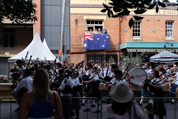A pipe band passes by people celebrating ANZAC Day at the Glenmore hotel in The Rocks, Sydney.