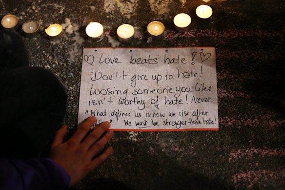 A person writes a message as people leave tributes at the Place de la Bourse following today's attacks.