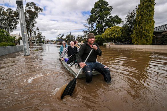 Tom Collins and mate Tim Tyler rescue Max and Julia Hastilow from floodwaters that have devastated the town of Rochester in central Victoria. 