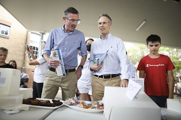 NSW Premier Dominic Perrottet (left) and candidate for Willoughby Tim James visit a cake stall at Cammeray Public School.