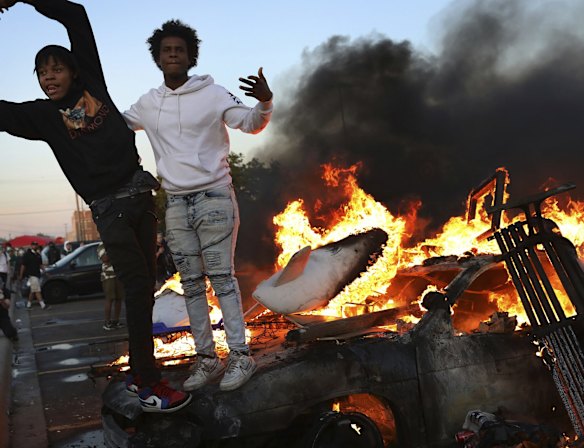 Young men stand atop a burning car in the Target parking lot during a third night of unrest.