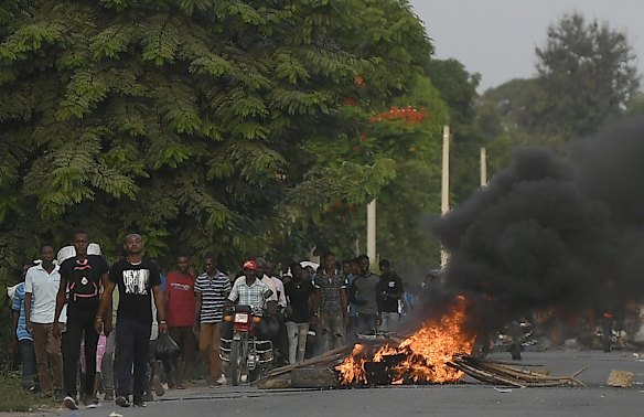 Men walk past a flaming barricade after violence broke out and hundreds of workers fled the area when demonstration near the home town of late President Jovenel Moise grew violent, ahead of his funeral in Quartier Morin in northern Haiti.