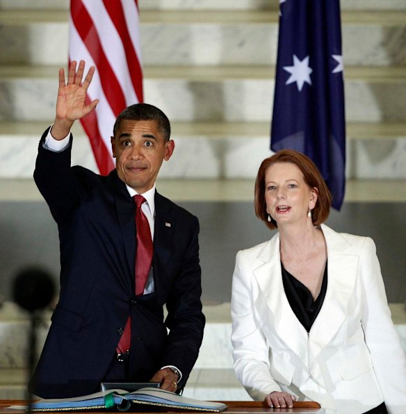 U.S. President Barack Obama waves to the public inside the Parliament House as Australia's Prime Minister Julia Gillard looks on in Canberra.