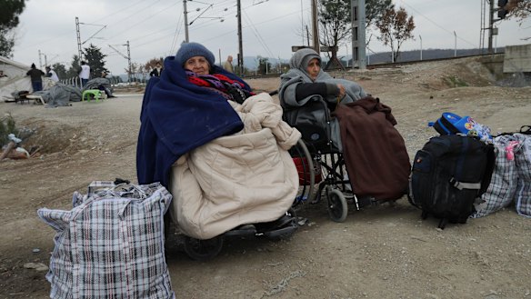 Refugees in wheelchairs wait to cross the border.