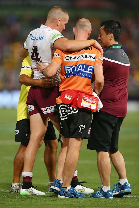 Clinton Gutherson of the Sea Eagles is helped from the field.