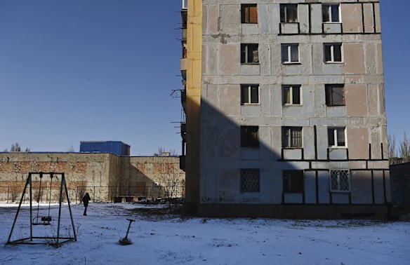 As the sounds of incoming artillery and air raid sirens fill the air, a man walks towards his apartment building in Avdiyivka.  