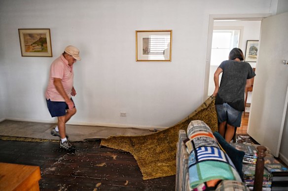 Family and friends of Colin Ambrosoli remove wet carpet at his Riverview Parade home which flooded yesterday during intense rainfall.