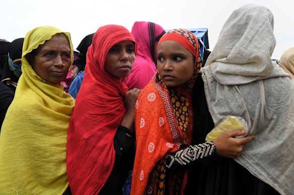 A Rohingya woman holding her ration cards in a plastic cover to protect it from the rain whilst in queue at a distribution site following a monsoonal downpour in Hakim Para Camp.