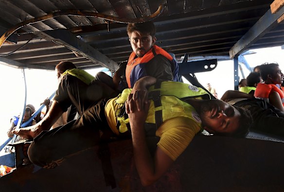 Exhausted refugees wait on the deck after being rescued.