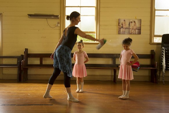 Ballet principal Virginia Guy sprays disinfectant on daughter Florence during class.