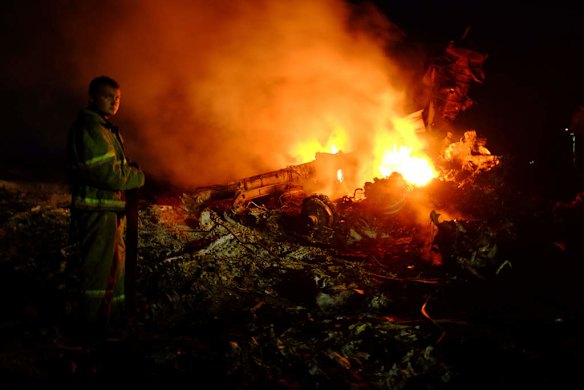 A firefighter stands as flames burst amongst the wreckages of the malaysian airliner.