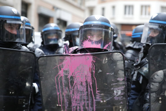 A riot police officer has his shield stained with pink painting during the protest. 
