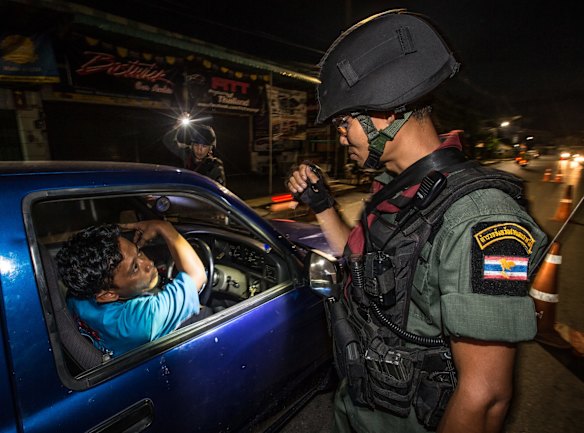 Thai soldiers patrol a roadblock looking for weapons or suspected insurgents. 
