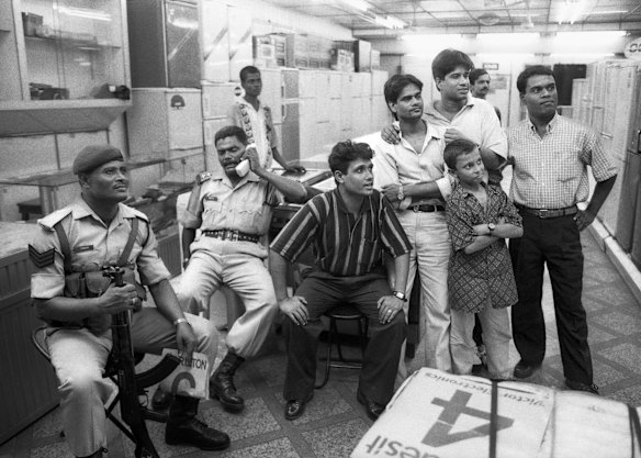 Office workers and policemen in Lahore watch the cricket on TV.