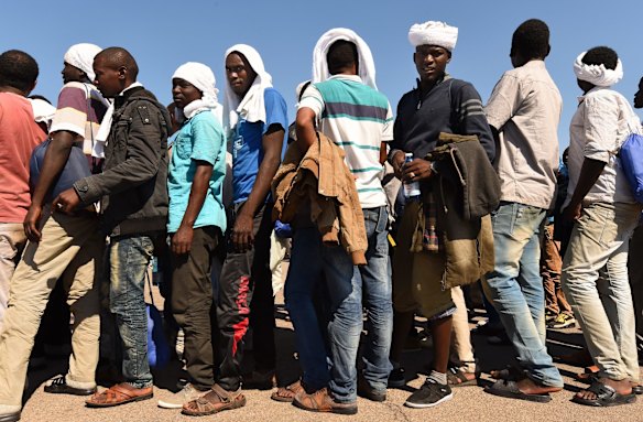 Some of the 415 people rescued off the Libyan coast by the Migrant Offshore Aid Station (MOAS) supported by Medecins Sans Frontieres (MSF) on the MY Phoenix wait to be assigned to a bus and reception centre moments after disembarking at Taranto port, Italy.