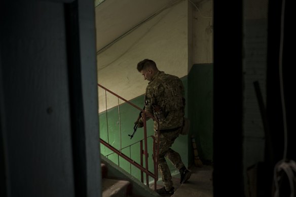 A Ukrainian serviceman walks inside a building after searching the apartment of a man suspected of being a Russian collaborator in Kharkiv.