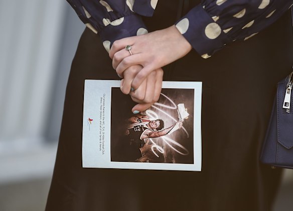 A woman holding the order service booklet.