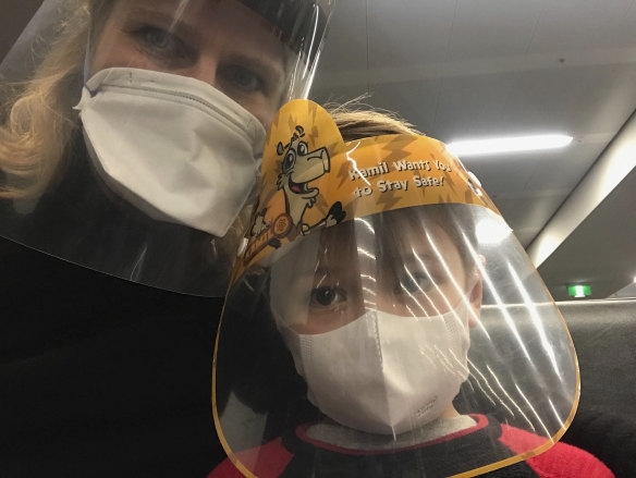 Astrid Magenau and son Hendrix wear a face mask and shield on-board their Qatar Airways flight from Germany to Sydney.