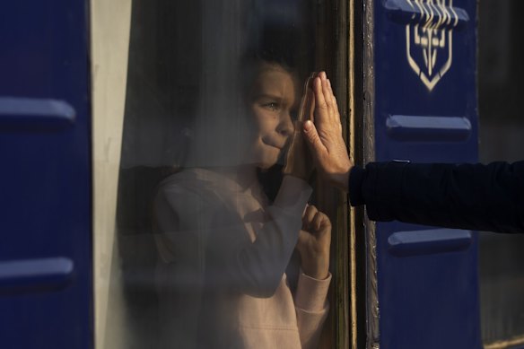 Russian Mishanin, right, bids farewell to his nine-year-old daughter as the train leaves with his family for Poland, at the train station in Odesa.