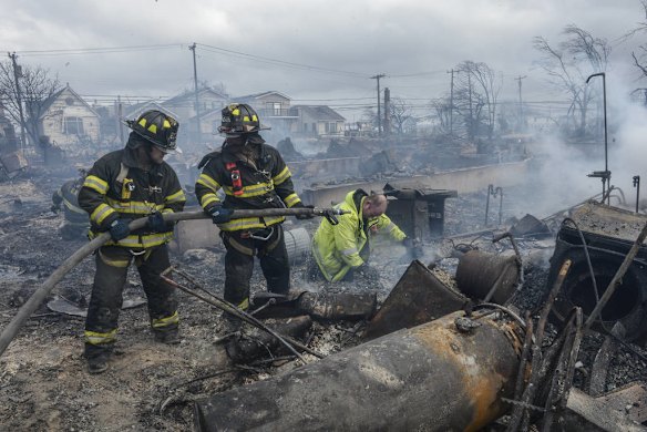 Firefighters look for hot spots in the remains of some of the dozens of homes destroyed by fire in Breezy Point in the Queens borough of New York